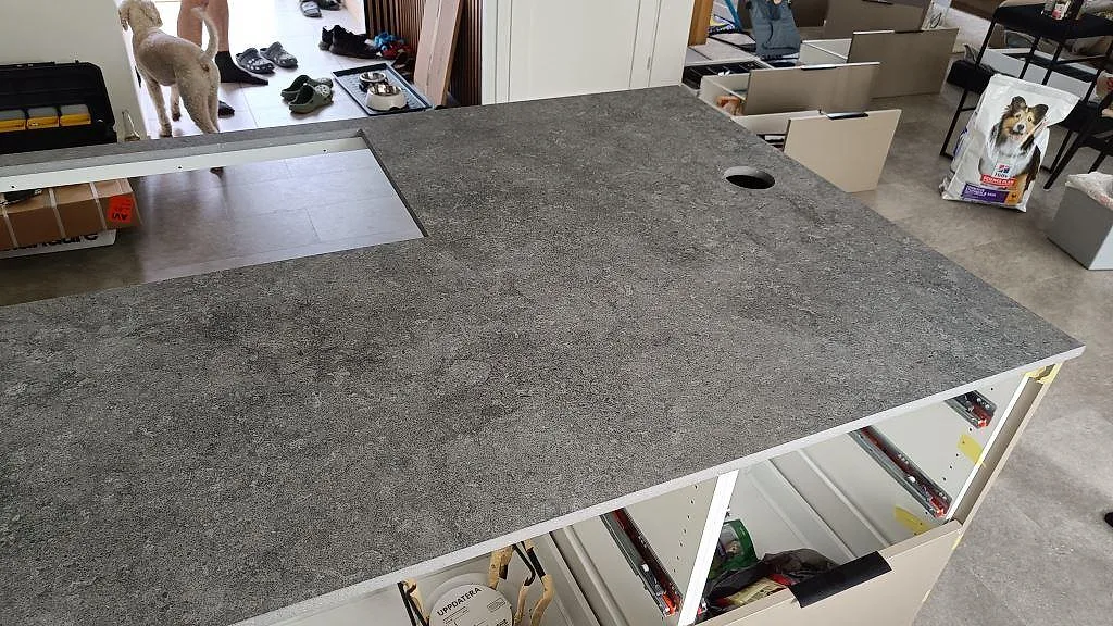 Grå köksbänkskiva i matt Dekton Vk04 Grafite med rund öppning och rektangulär utskärning under montering i Höllviken.