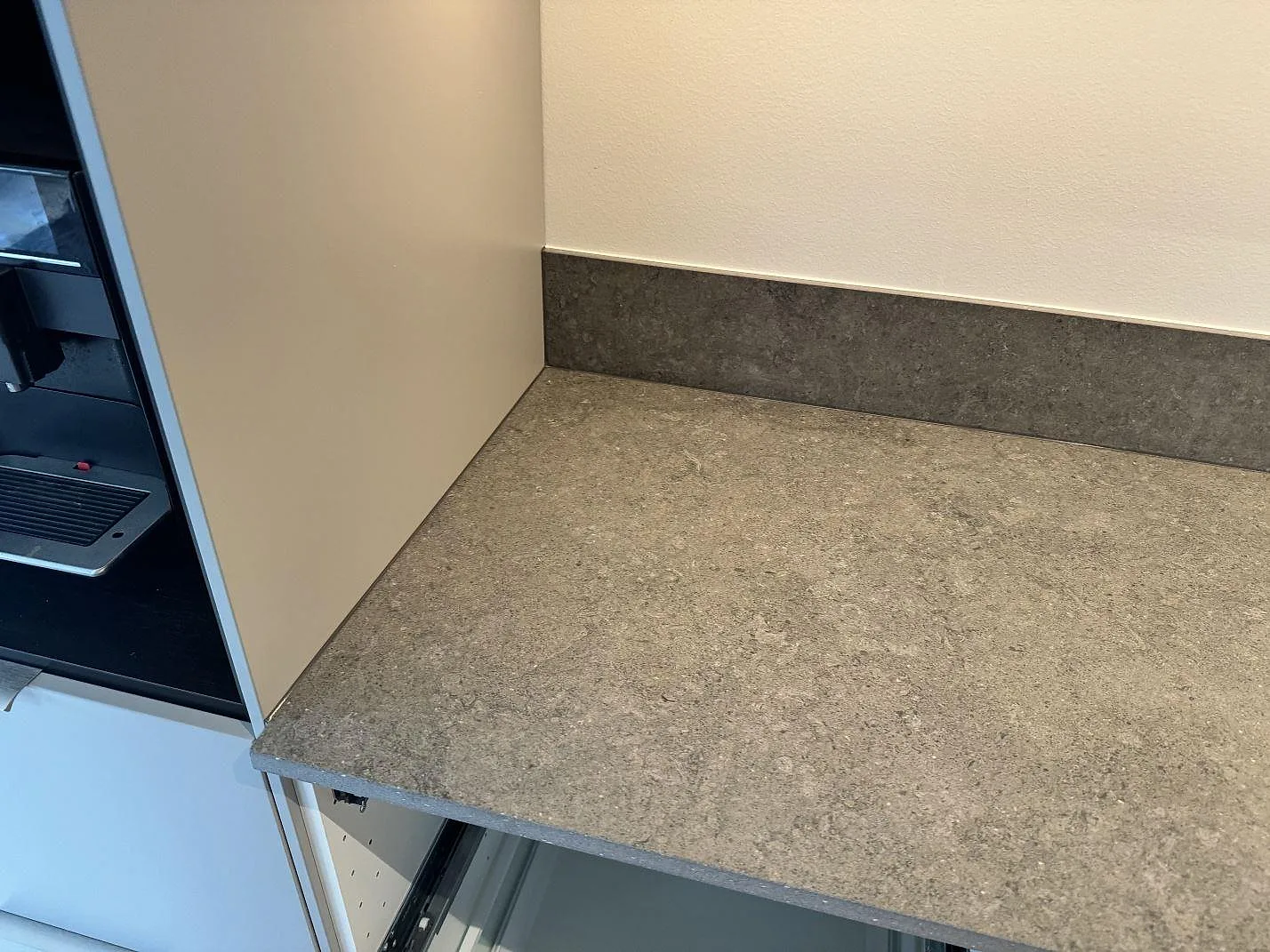 Arbetsyta i matt Dekton Vk04 Grafite med 12 mm stänkskydd mot vägg vid högskåp i köket i Lomma.