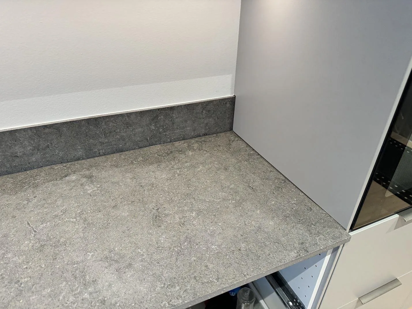 Närbild på matt Dekton Vk04 Grafite som bänkskiva och stänkskydd i ett hörn av köket i Lomma.