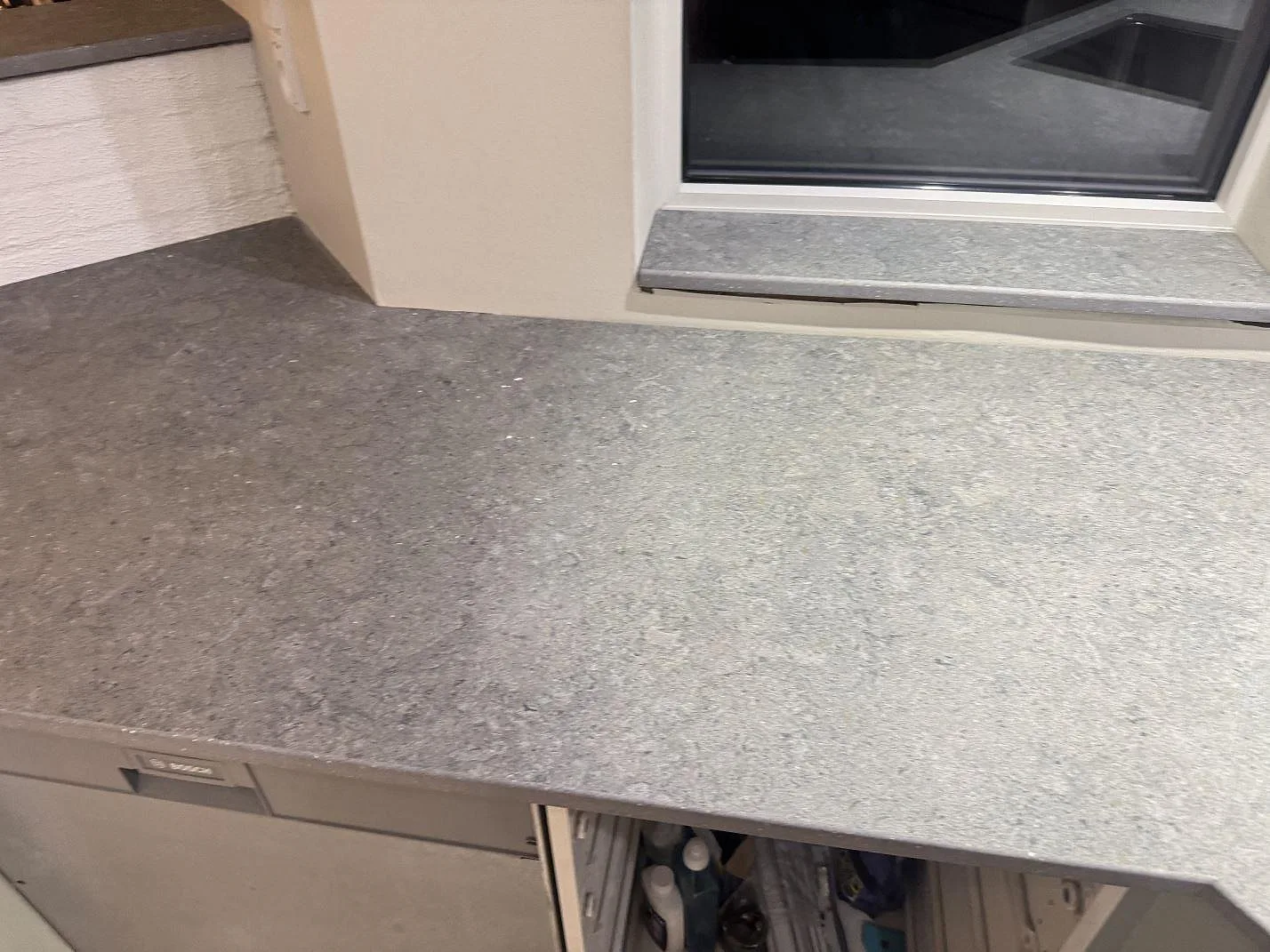 Bred arbetsyta i matt Dekton Vk04 Grafite under fönster, grå keramisk köksbänkskiva i Ølsted.