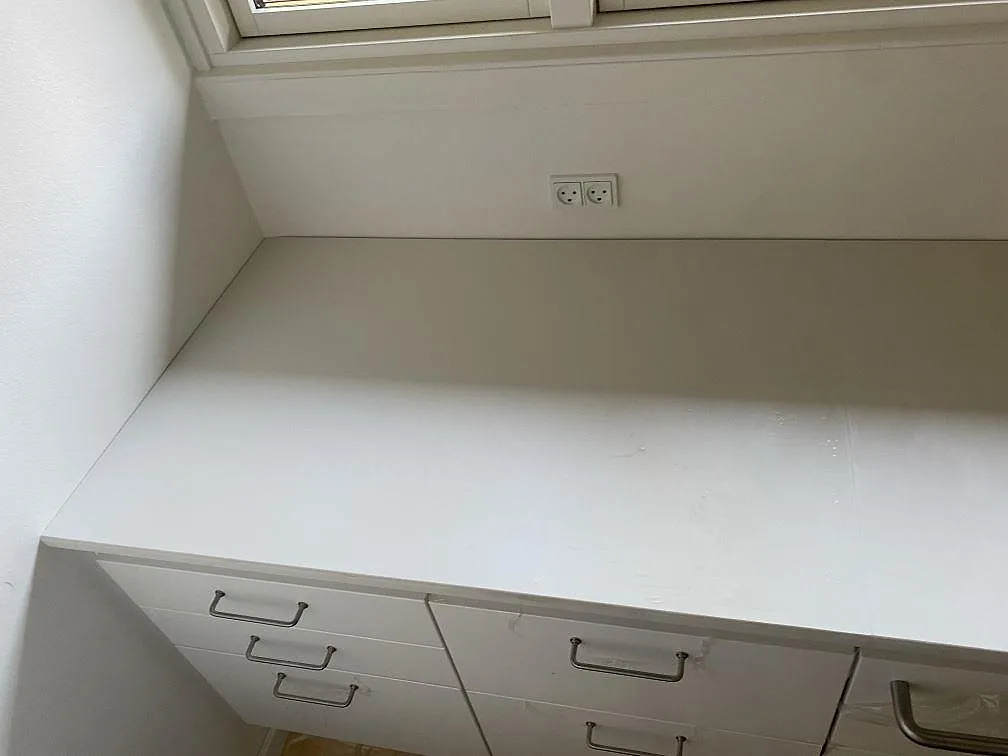 Rak bänkrad i matt Dekton Zenith vid fönster med vita köksfronter och synlig montering i Holte.
