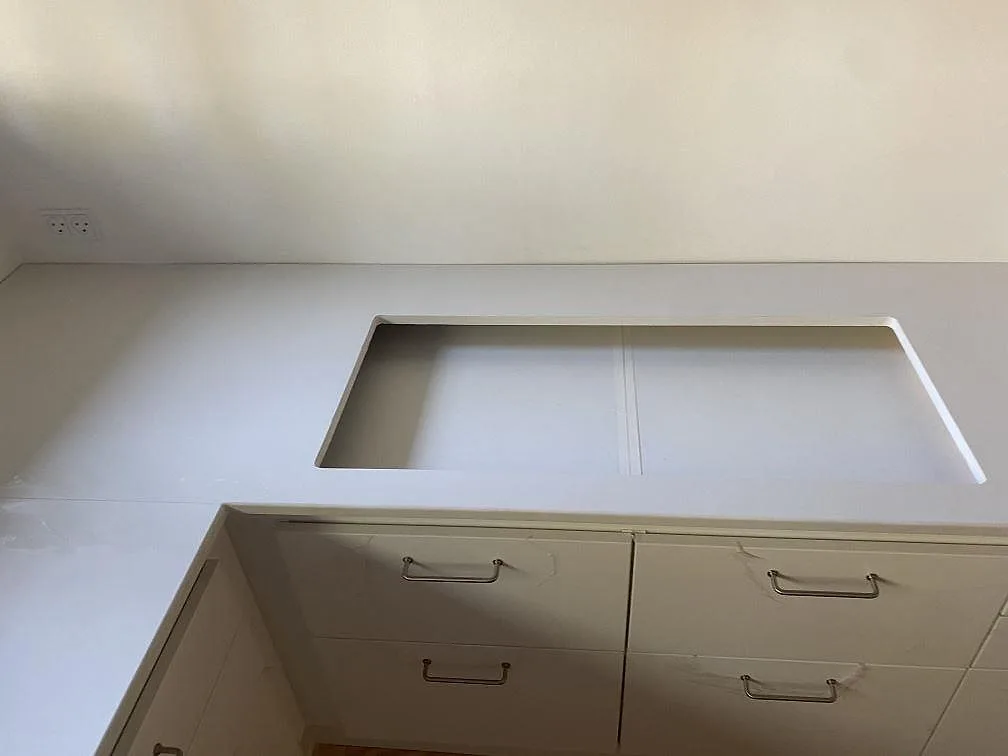 Matt vit Dekton Zenith köksbänkskiva i Holte med utskuren öppning för häll framför vita köksfronter.