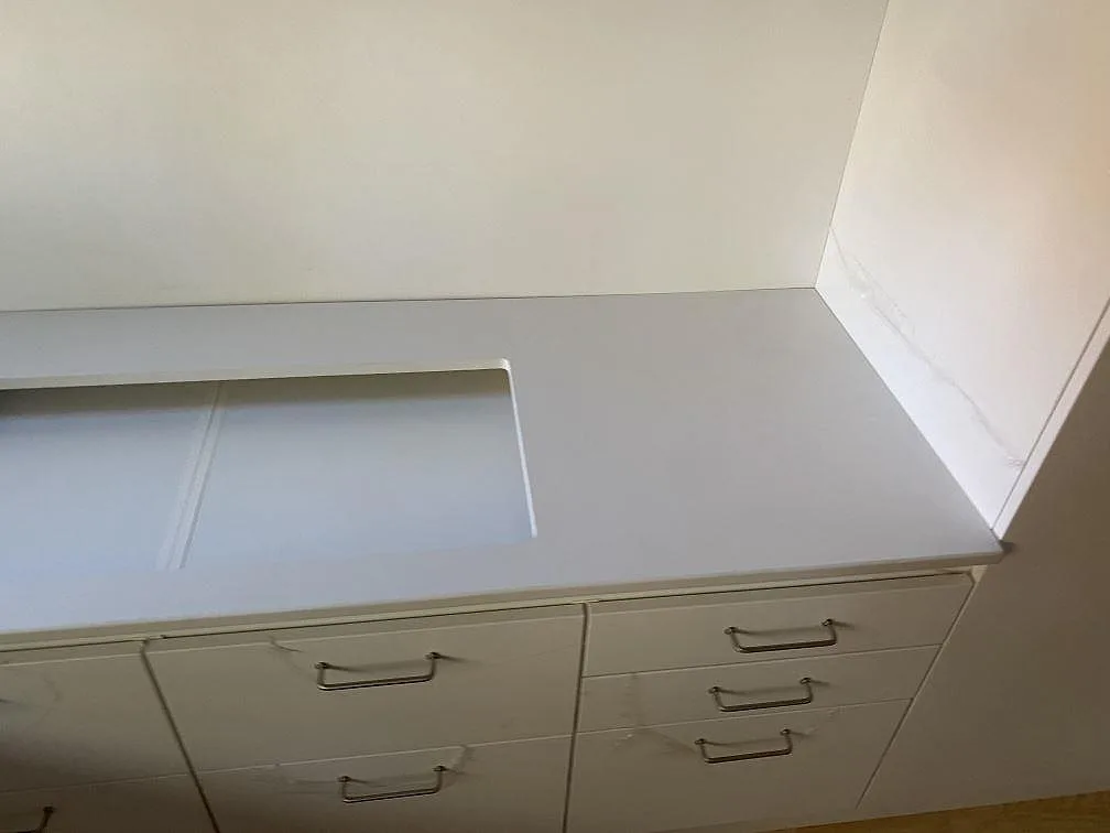 Detalj av matt Dekton Zenith köksbänkskiva i Holte med hällöppning och vita lådfronter under stenen.