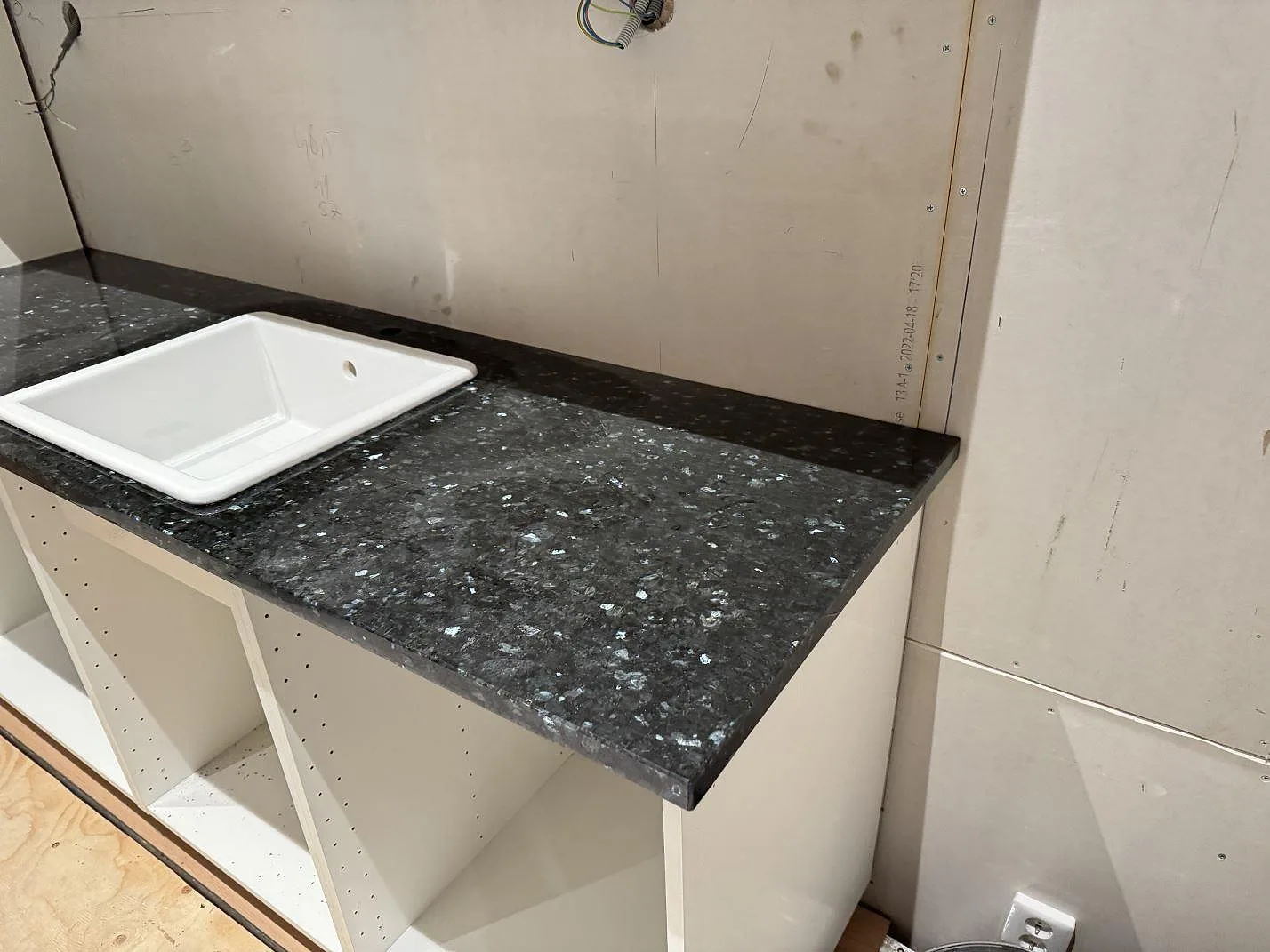 Bänkskiva i polerad Emerald Pearl granit med vit ho och låg stänkkant i Genarp.