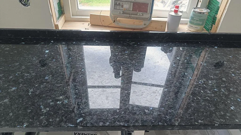 Blank Emerald Pearl granit i kök i Hönö med tydliga blågröna mineralfält och reflektion från fönster.