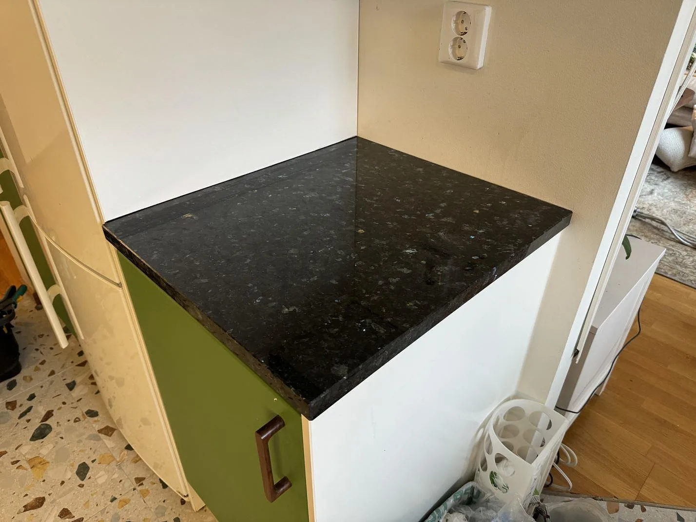 Sidobänk i polerad Emerald Pearl granit monterad på grönt köksskåp i Lund.