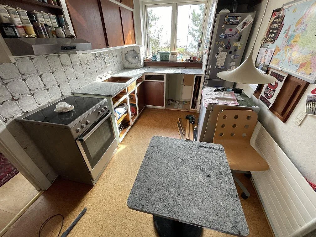 Köksbänkskiva i polerad Emerald Pearl granit med separat bordsskiva och väggbänkar i ett kök i Ringsted.
