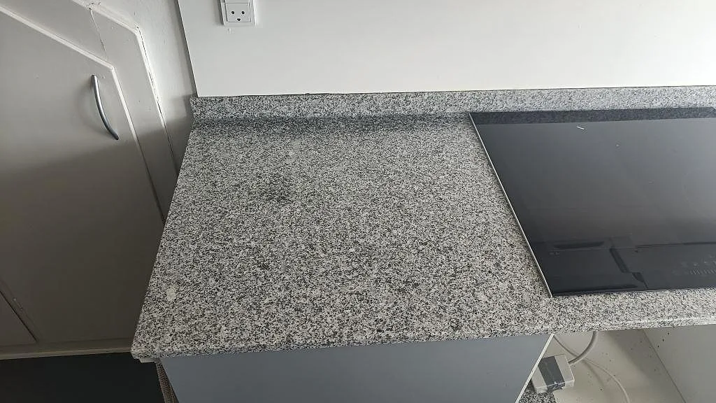 Närbild på köksbänkskiva i grå granit Grigio Cristallo med spräcklig kornstruktur och matt yta i ett kök i Gentofte.