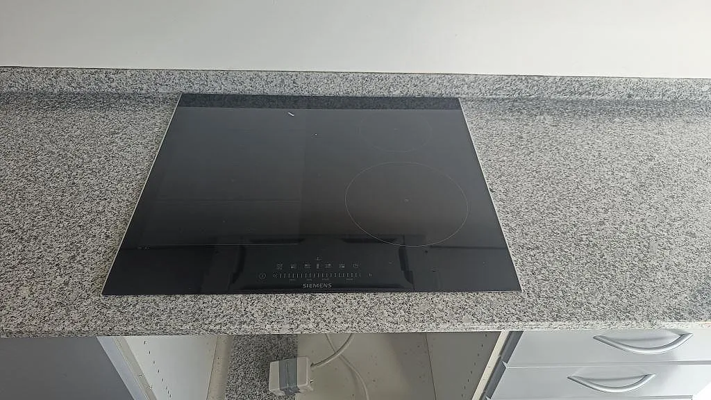 Infälld Siemens induktionshäll i en köksbänkskiva av grå granit Grigio Cristallo, sedd ovanifrån, i ett kök i Gentofte.