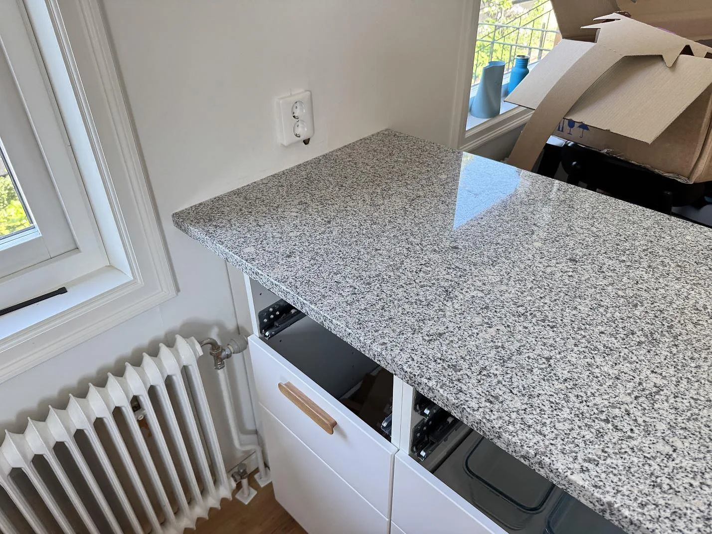 Polerad Grigio Cristallo granit på bänkparti vid radiator och fönster i ett kök under montering i Hjärup.