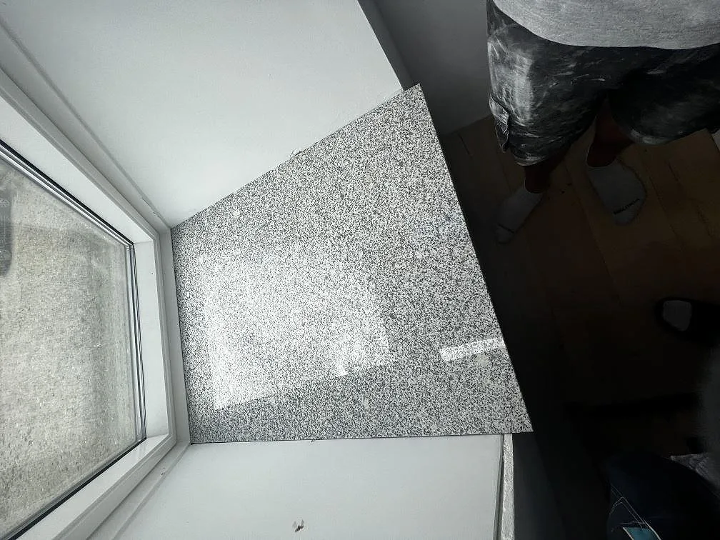 Polerad Grigio Cristallo granit installerad vid ett fönster, fotograferad ovanifrån under montering i Kirke Hyllinge.