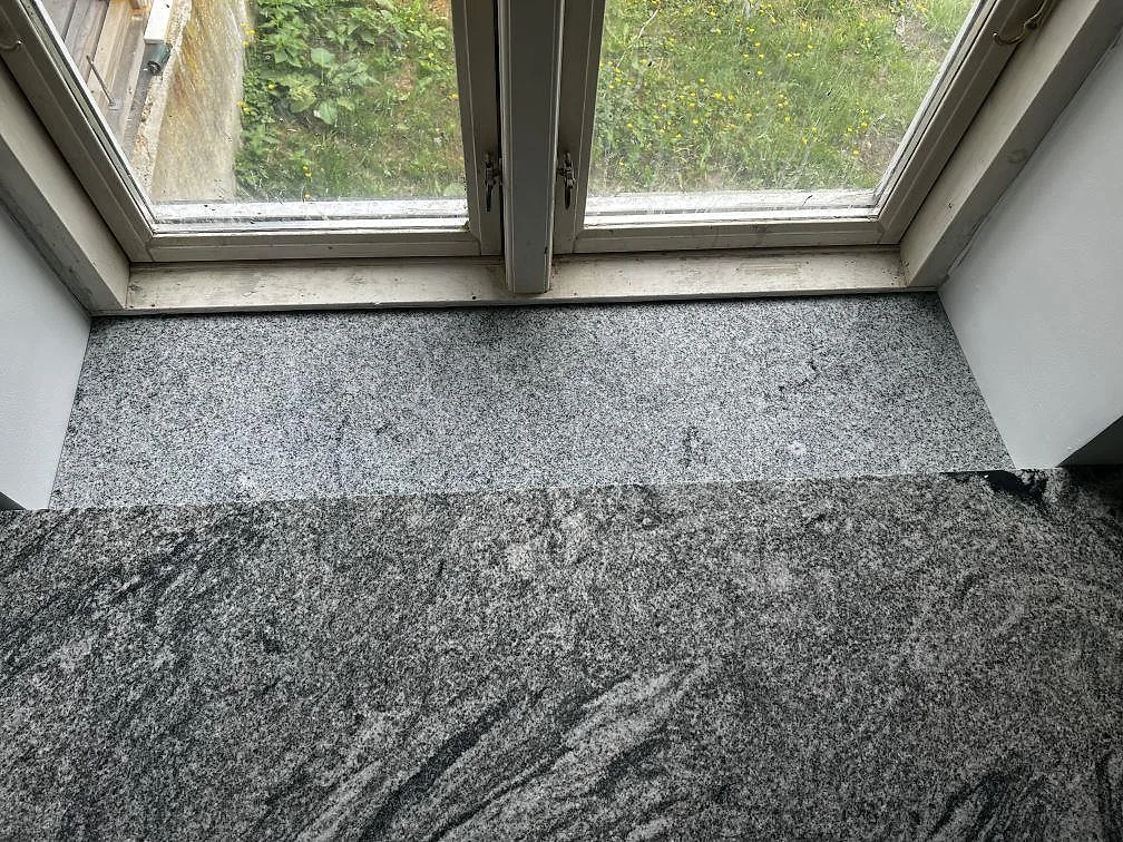 Ytbild av polerad Grigio Cristallo granit vid fönsterbänk och köksbänk i Kirke Hyllinge.