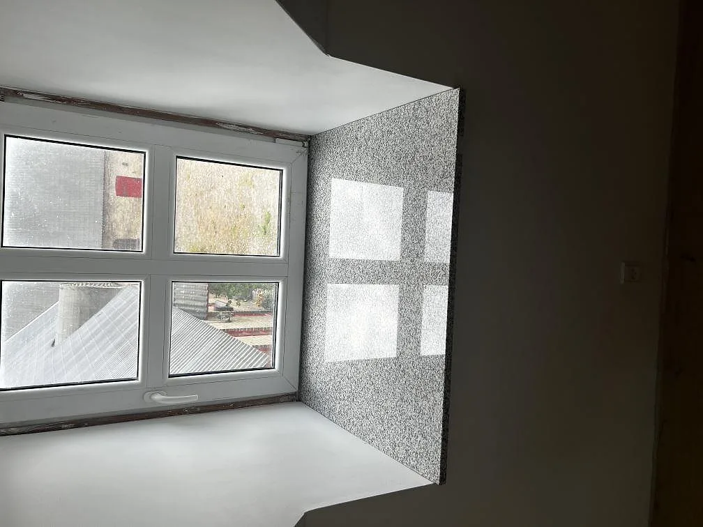 Installerad Grigio Cristallo granit vid fönster med blank polerad yta och ljusgrå stenstruktur i Kirke Hyllinge.