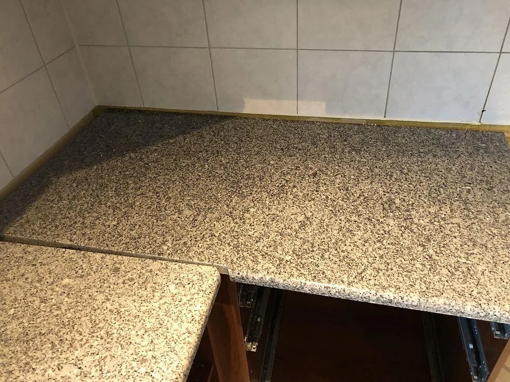 Polerad granitbänkskiva i Grigio Cristallo mot kaklad vägg i ett kök i Onsala.