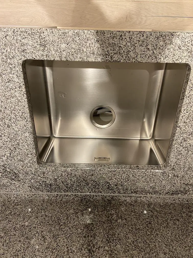 Underlimmad rostfri Blanco Andano-diskho infälld i polerad Grigio Cristallo bänkskiva i ett kök i Ystad.