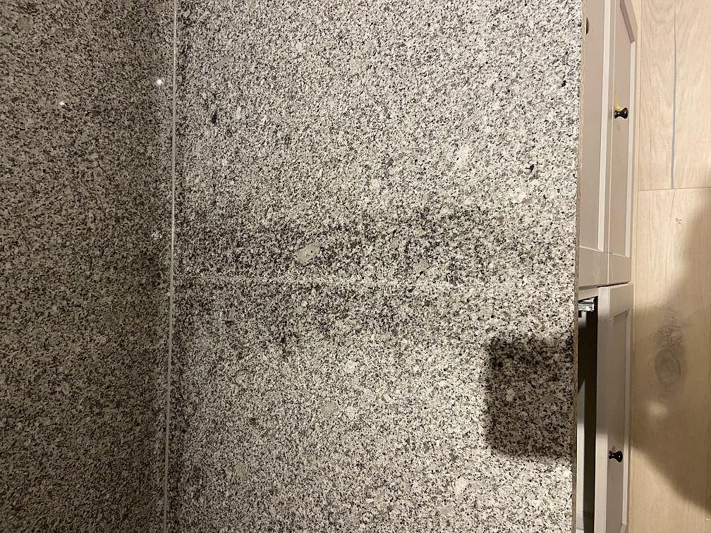 Närbild på polerad Grigio Cristallo granit med ljust grått kristallint korn där bänkskiva möter uppvikt stänkskydd i ett kök i Ystad.