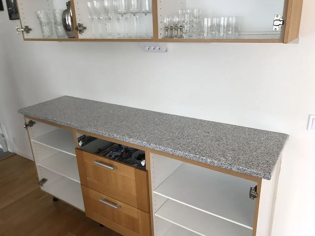Köksbänkskiva i grå granit Gris Cordoba, polerad, nylagd på en köksbänk med ekfronter och överskåp i ett kök i Klagshamn.