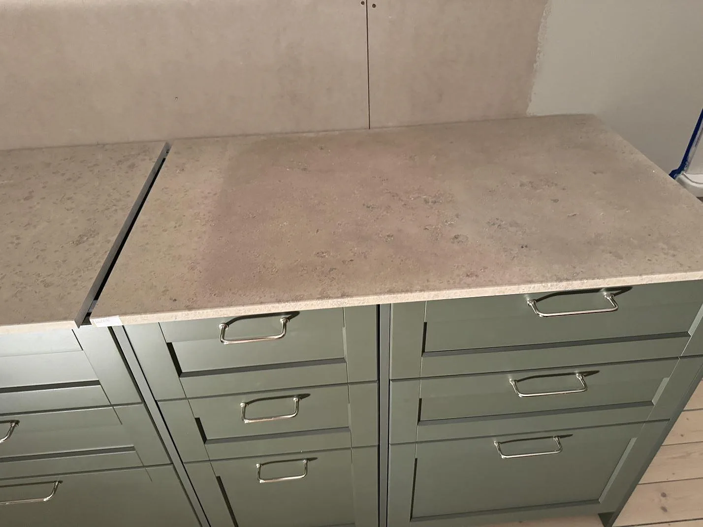 Närbild av matt Jura Grey kalksten på gröna kökslådor med naturstensmönster i Älmhult.