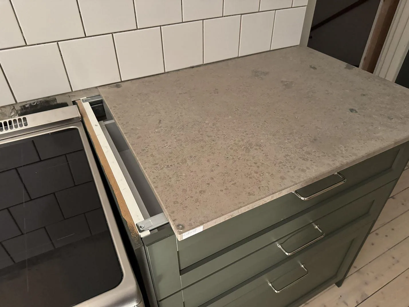 Matt Jura Grey kalksten som arbetsyta intill fristående spis och vit kakelvägg i Älmhult.