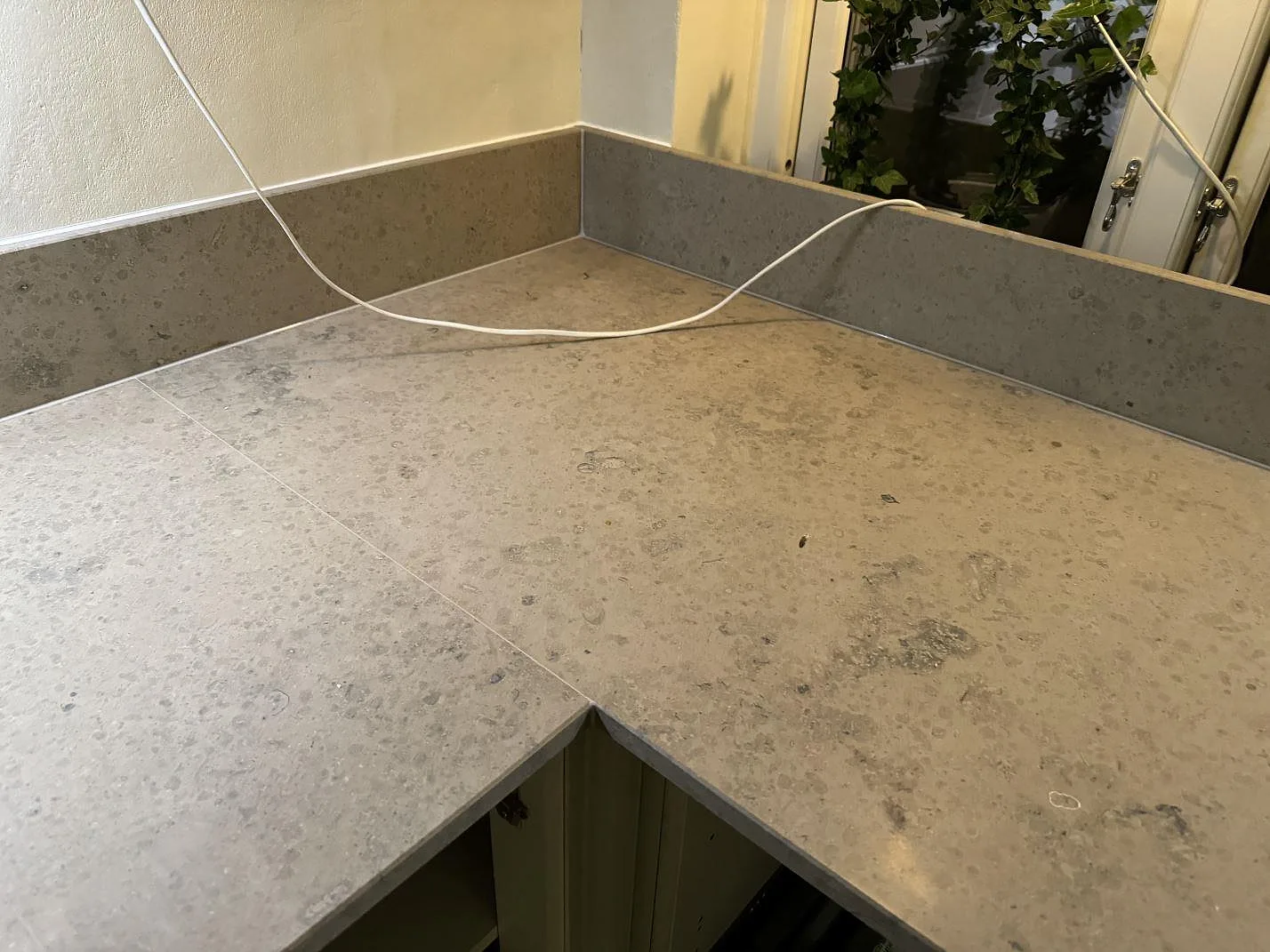 Hörndel av köksbänkskiva i matt Jura Grey kalksten med uppvikt stänkkant i Ängelholm.