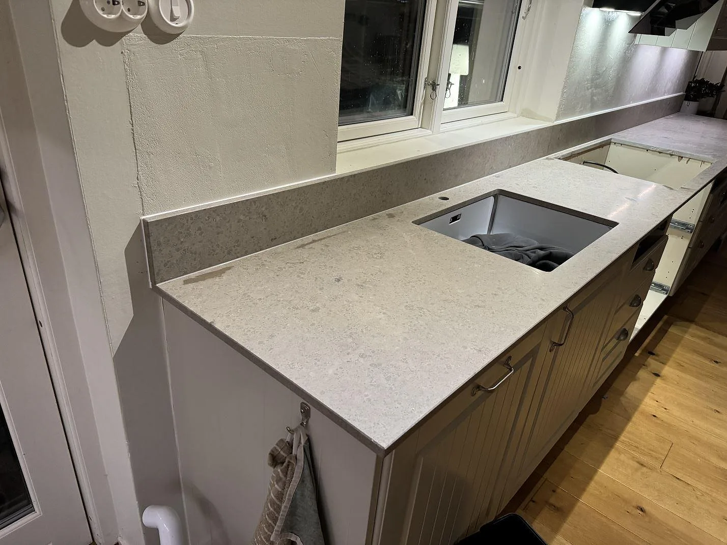 Köksbänkskiva i matt Jura Grey kalksten med underlimmad rostfri diskho och uppvikt stänkkant i Ängelholm.