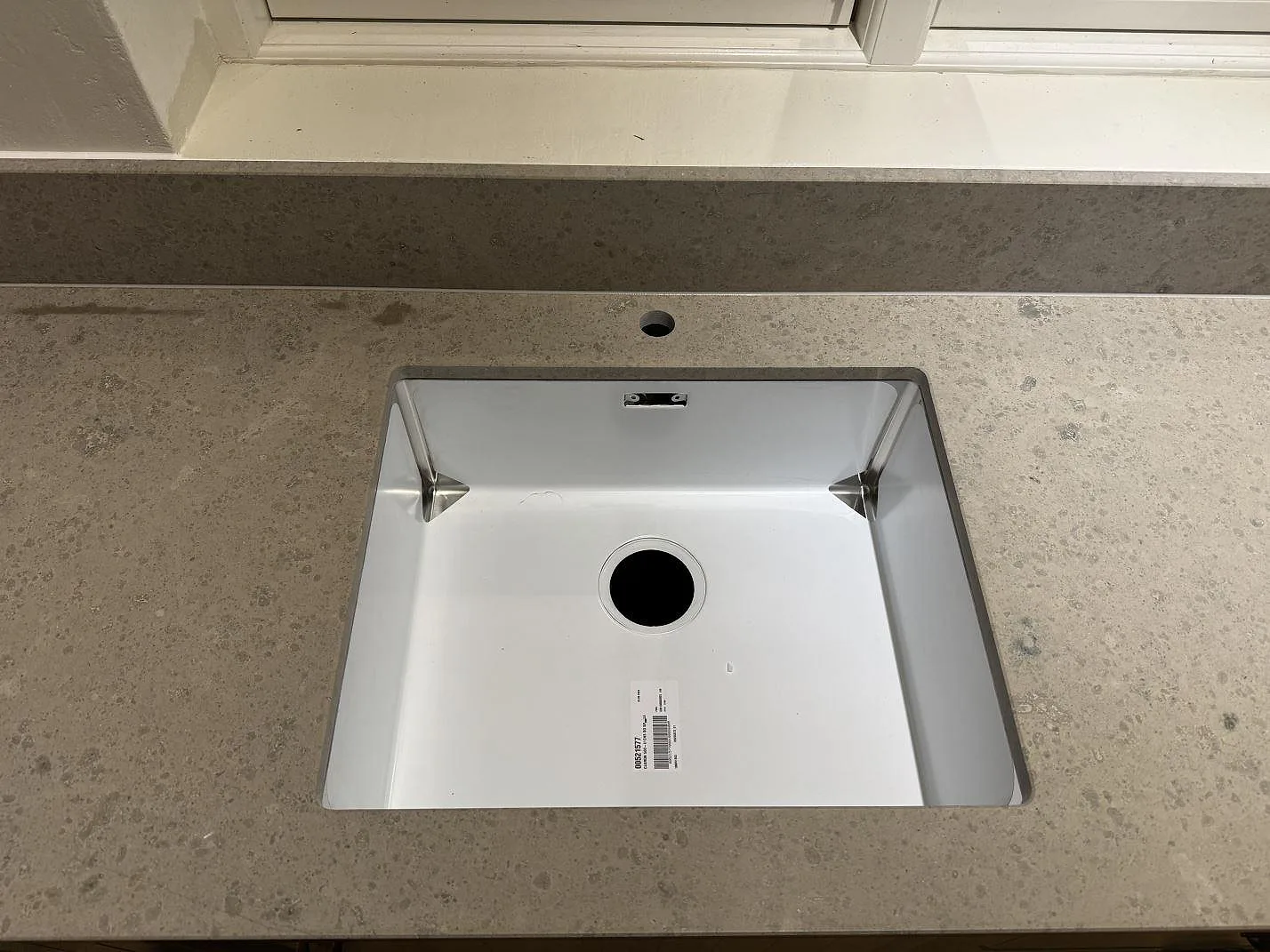 Närbild på underlimmad rostfri diskho i matt Jura Grey kalkstensbänkskiva i ett kök i Ängelholm.