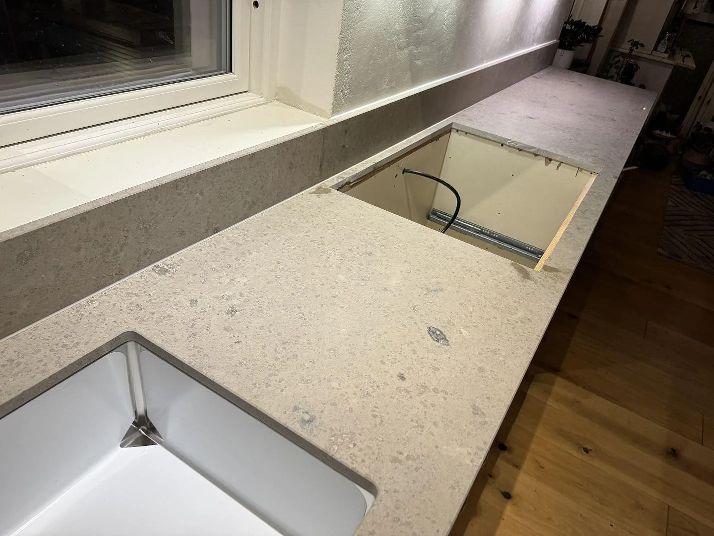 Matt köksbänkskiva i Jura Grey kalksten med diskho, hälluttag och fönsterrad under montering i Ängelholm.