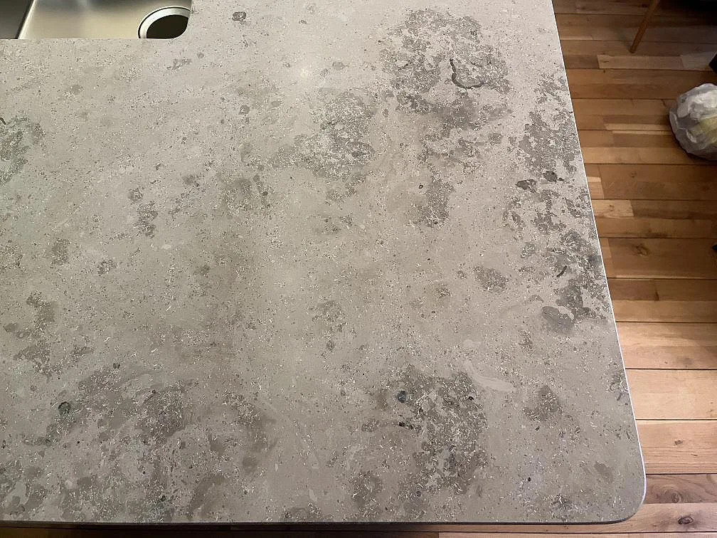 Hörn av en matt Jura Grey bänkskiva i kalksten med tydlig fossil ådring i ett kök i Båstad.