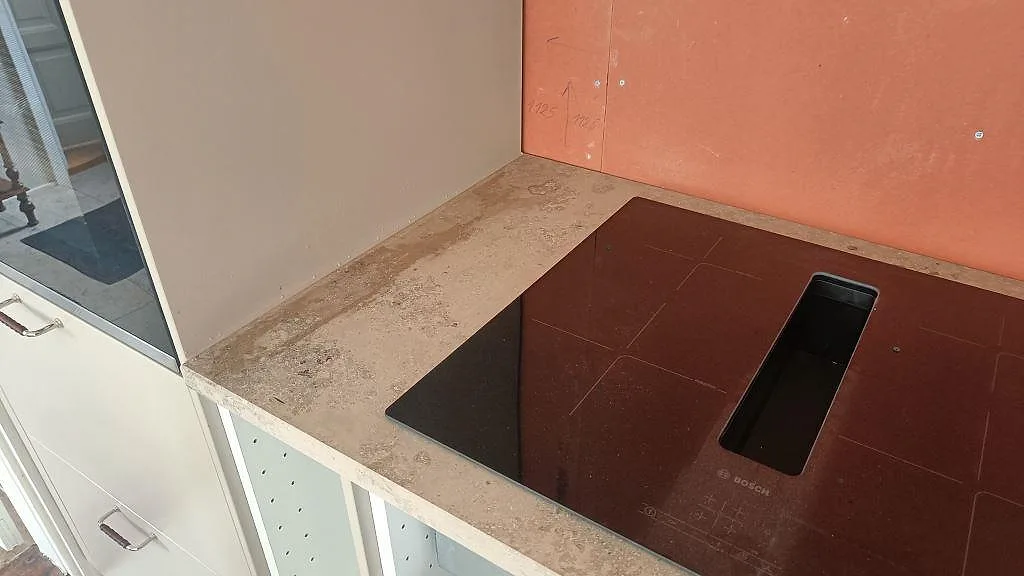 Infälld Bosch induktionshäll i en köksbänkskiva av Jura Grey kalksten med uppvikt stänkkant i Båstad.