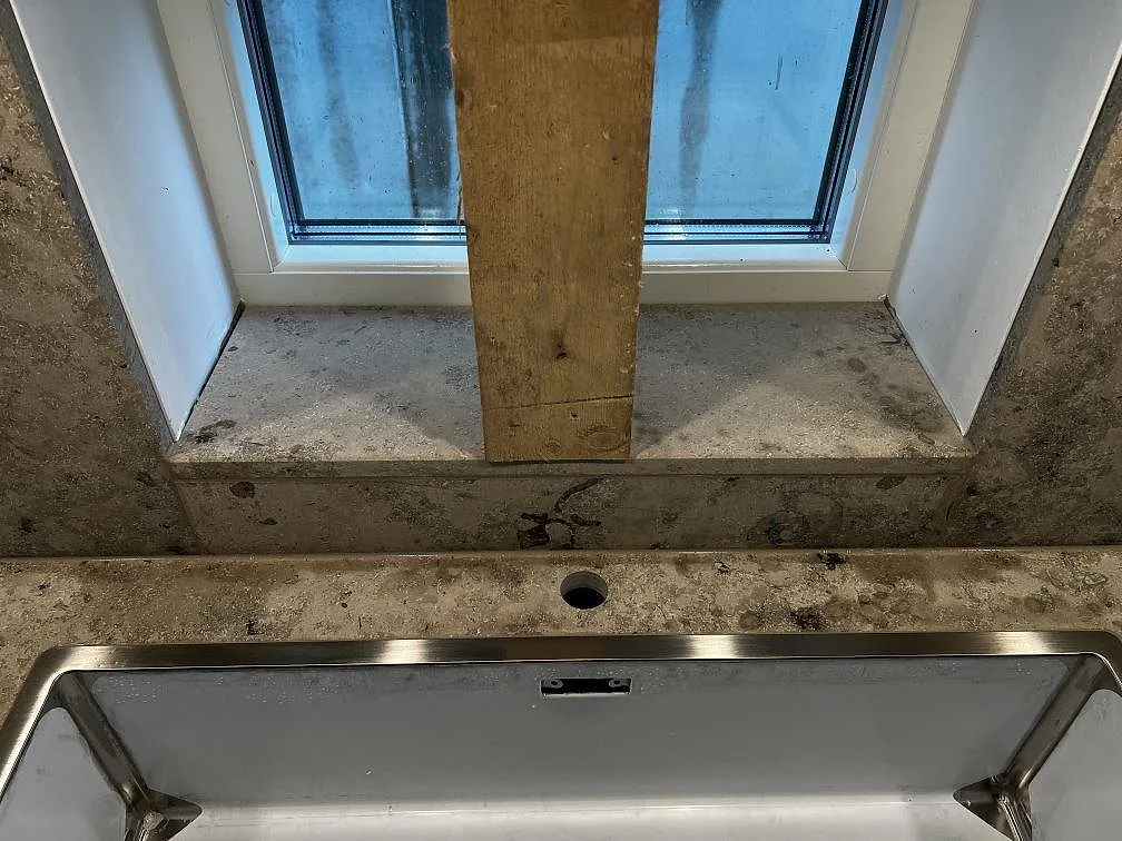 Detaljbild av matt Jura Grey kalksten vid diskho och fönsterbröstning i köket i Bankeryd.