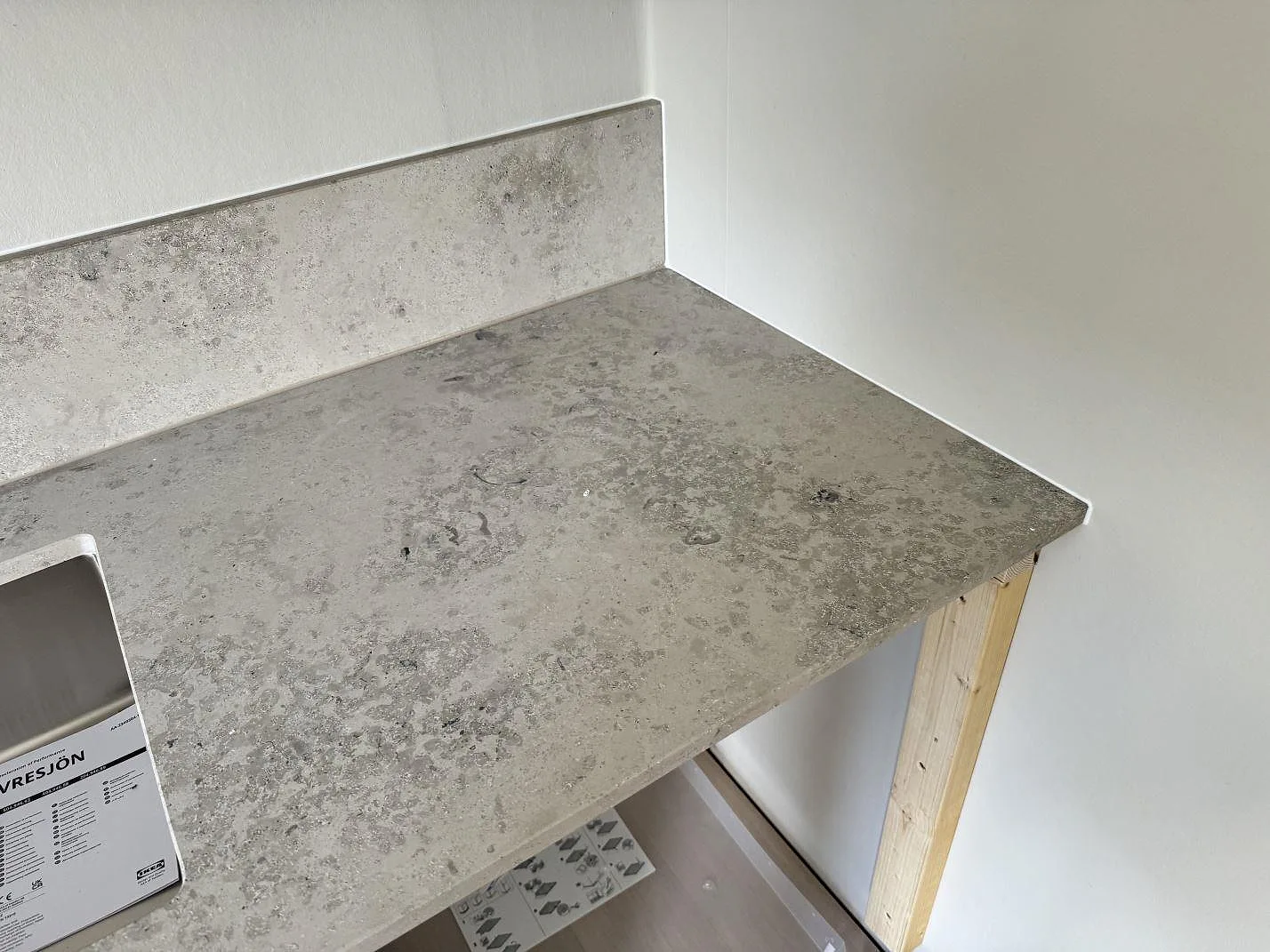 Detalj av matt Jura Grey bänkskiva och stänkskydd vid diskho under montering i bodafors.