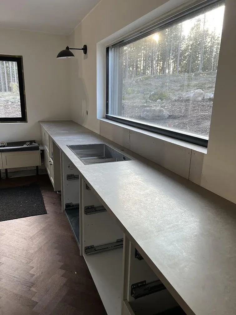Närbild på matt Jura Grey kalksten med underlimmad rostfri diskho och vita köksstommar i Borås.