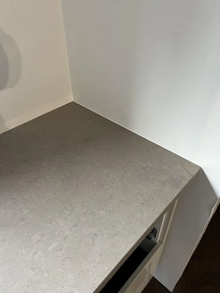 Detalj av köksö i matt Jura Grey kalksten med tjock framkant och vita stommar i Borås.