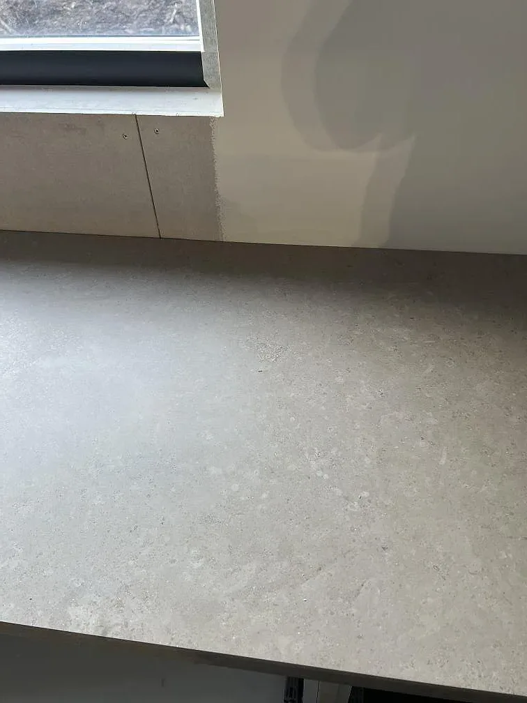 Närbild på den matta Jura Grey kalkstensytan vid vägg och fönster under köksmontering i Borås.