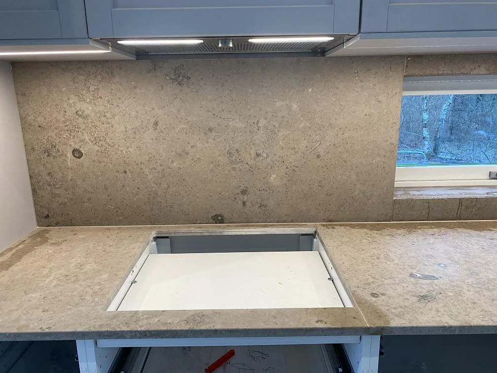 Stänkskydd och bänkskiva i matt Jura Grey kalksten med synliga fossilavtryck i ett kök i Brösarp.