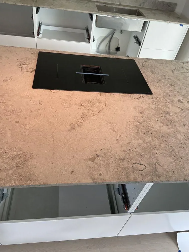 Matt Jura Grey köksbänkskiva med infälld svart induktionshäll och öppna köksstommar i Bunkeflostrand.