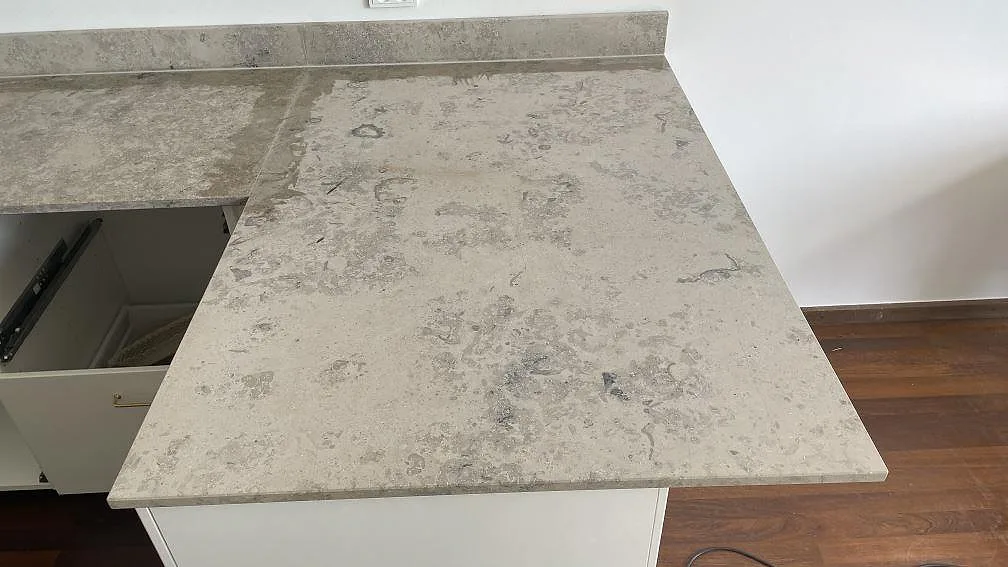 Matt köksbänk i Jura Grey som vänder runt ett hörn i Espergærde, med uppvikt stänkkant och öppna köksstommar under montering.