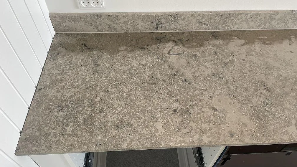 Matt Jura Grey köksbänk längs en vit panelvägg med uppvikt stänkkant och eluttag i ett kök i Espergærde.