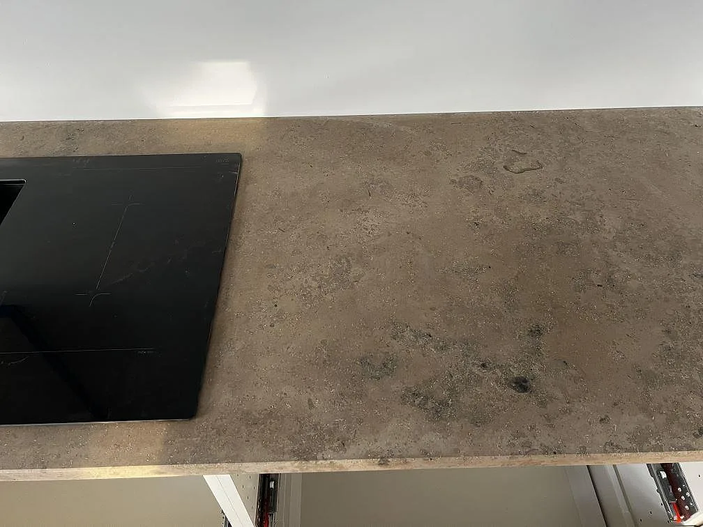 Detalj av matt Jura Grey köksbänkskiva med induktionshäll och synlig stenstruktur i Falsterbo.