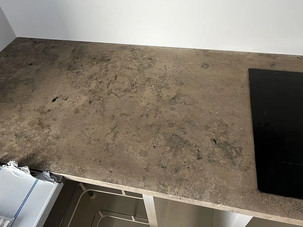 Matt Jura Grey bänkskiva med fossil teckning och del av induktionshäll i ett kök i Falsterbo.