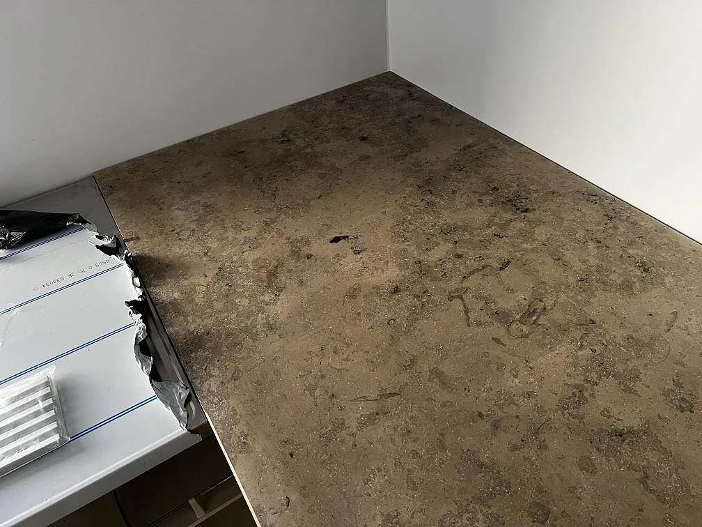 Hörnvy av matt Jura Grey kalkstensbänkskiva med taupegrå yta under montering i Falsterbo.