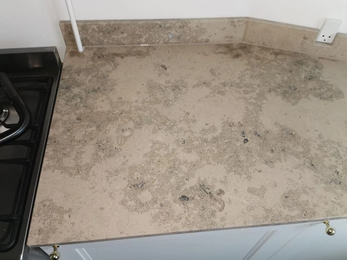 Matt Jura Grey köksbänkskiva sedd ovanifrån med tydlig fossilådring och uppvikt stänkkant intill en fristående spis i ett kök i Frederiksberg.