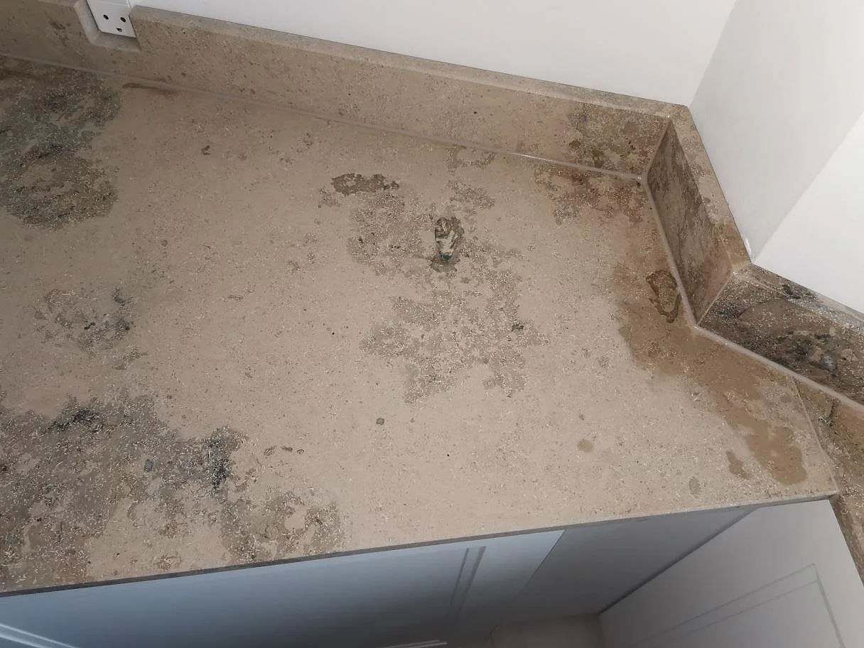 Hörn av Jura Grey köksbänkskiva i matt kalksten med uppvikt stänkkant och fossilmönstrad yta i ett kök i Frederiksberg.