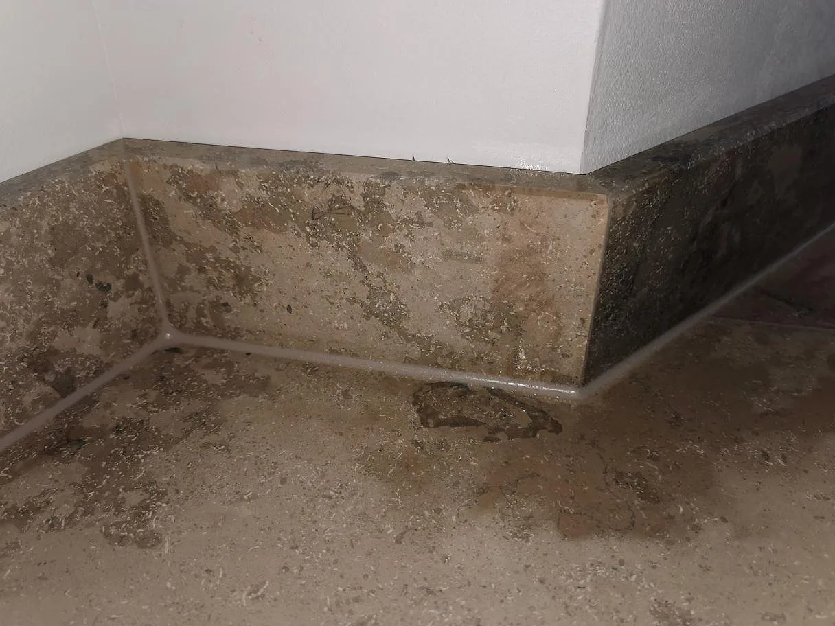 Jura Grey köksbänkskiva i matt kalksten vid fönsterläget med uppvikt stänkkant och naturlig fossilstruktur i ett kök i Frederiksberg.