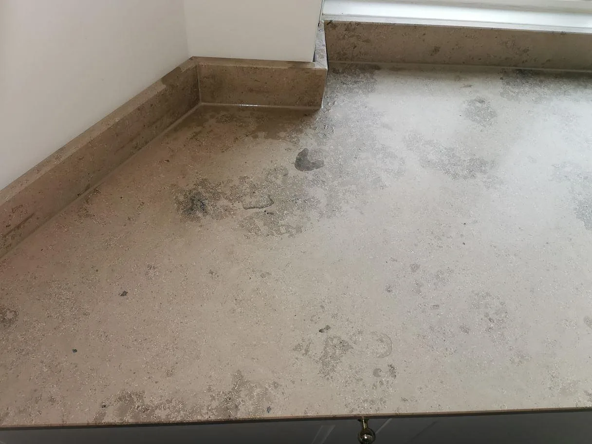 Detalj av Jura Grey köksbänkskiva i matt kalksten med uppvikt stänkkant runt ett hörn i ett kök i Frederiksberg.