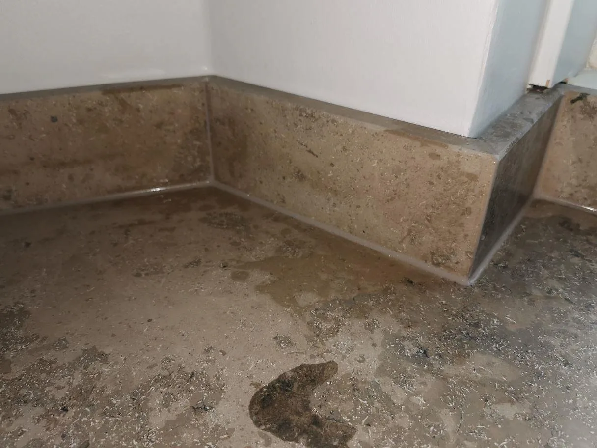 Uppvikt stänkkant i matt Jura Grey kalksten längs väggen i ett kök under montering i Frederiksberg.