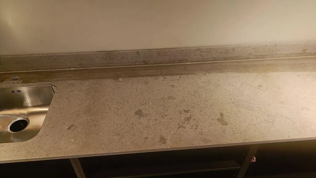 Lång arbetsyta i matt Jura Grey kalksten med låg stänkkant och naturliga fossilteckningar i ett kök i Göteborg.