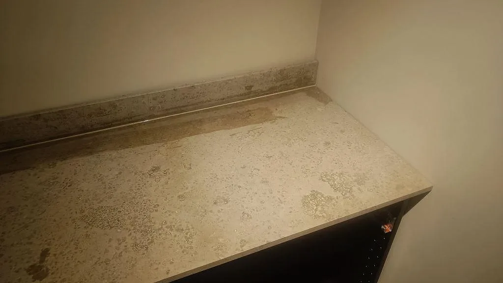Höger del av köksbänkskiva i matt Jura Grey kalksten med stänkkant mot ljus vägg i Göteborg.