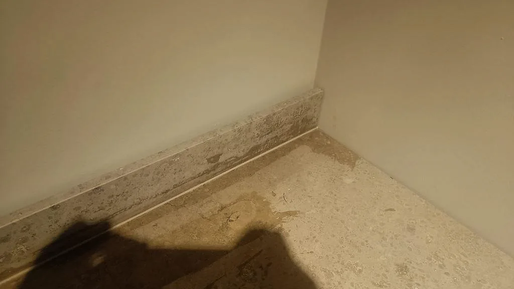 Detalj där den matta Jura Grey stänkkanten möter bänkskivan i kalksten i ett kök i Göteborg.