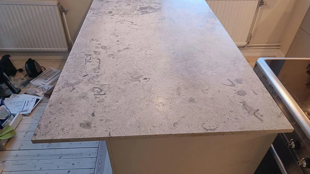 Ovanifrånvy av köksö i matt Jura Grey kalksten, 20 mm, med naturliga fossilmönster i Göteborg.